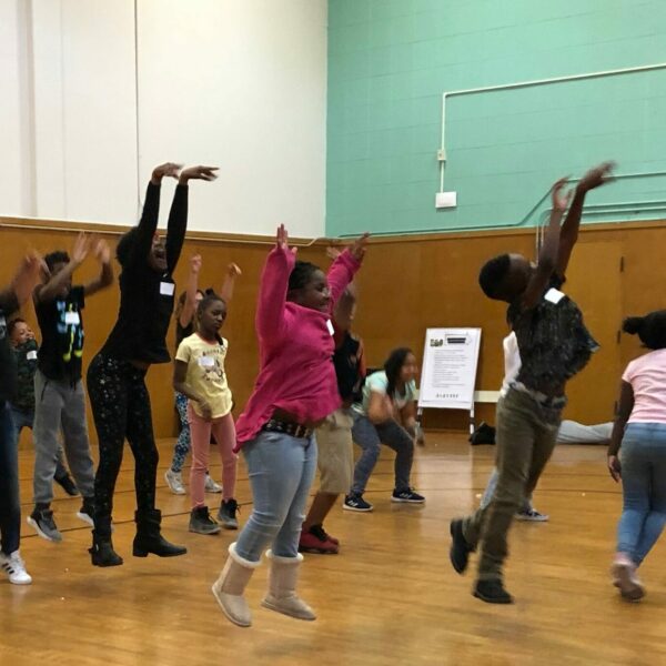 2-YCD Burckhalter Mach 2020 Young students perform jump with hands up high.