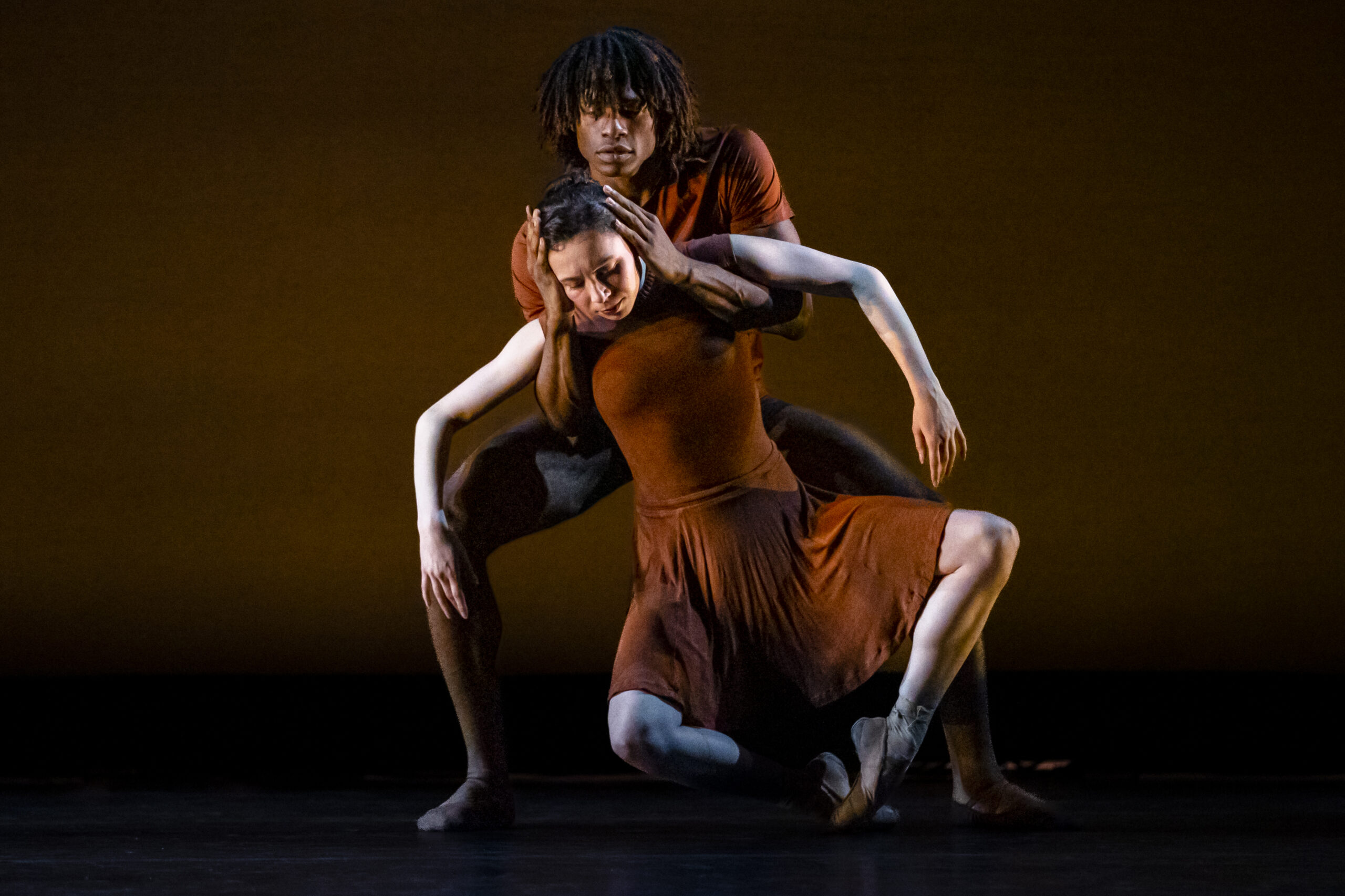_36I0157 A duet of OBC Dancers in brown costumes dancing low to the ground.