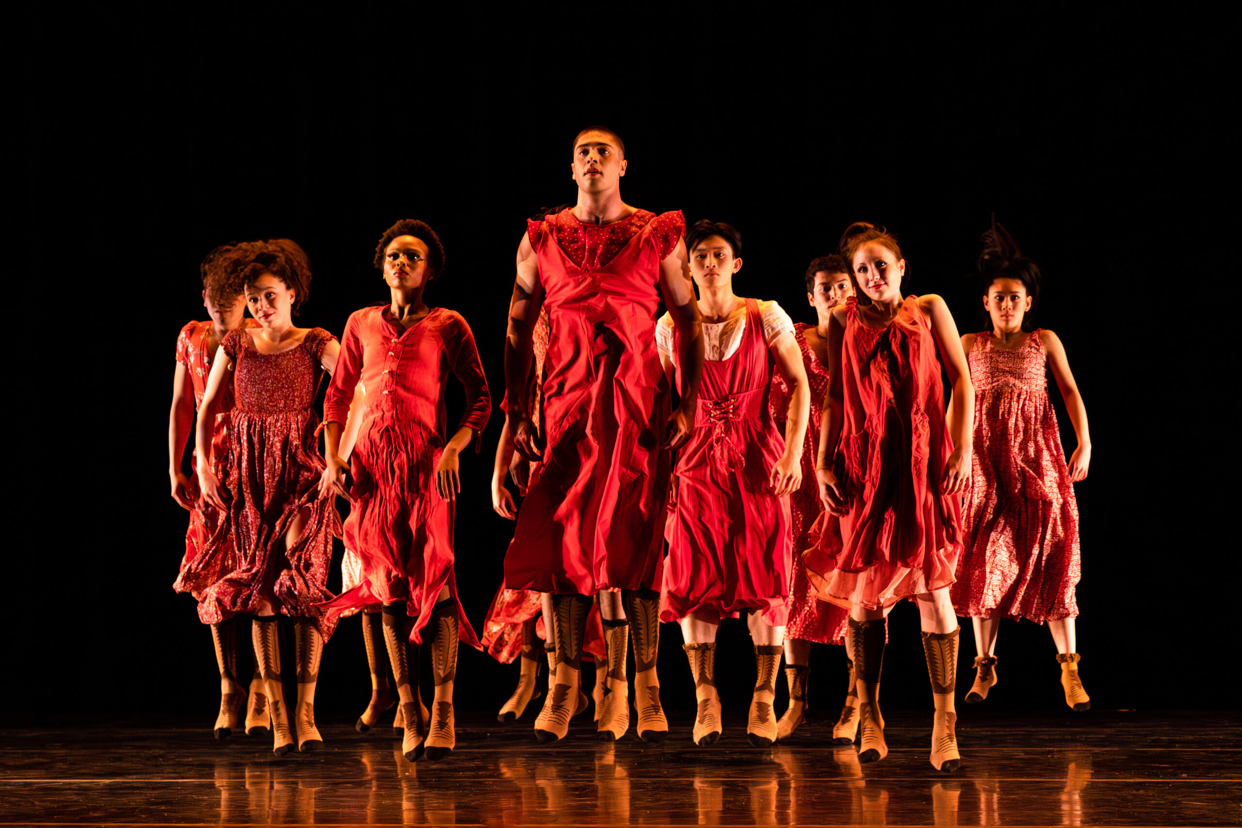 _36I0582-Enhanced-NR Full Company in Red costumes performing a hopping movement