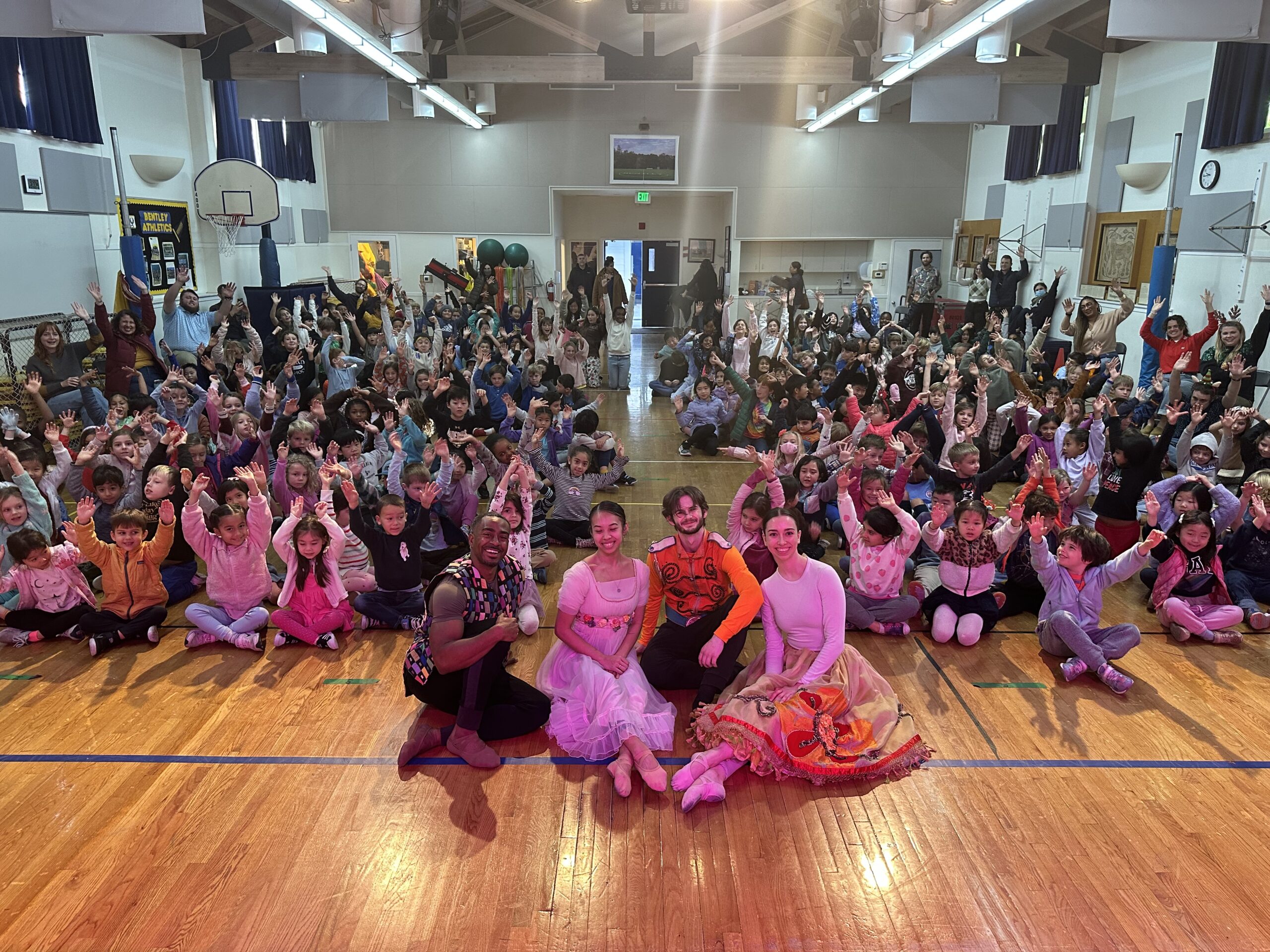 OBC dancers posing with students during an in-school assembly